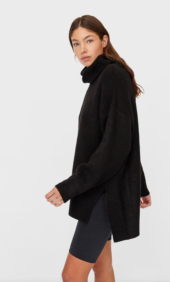 Diseño oversize con cuello cisne y manga larga para este jersey negro de Stradivarius con bajo asimétrico con aberturas laterales. Tiene un precio de 25,99 euros y está disponible en las tallas S y M.