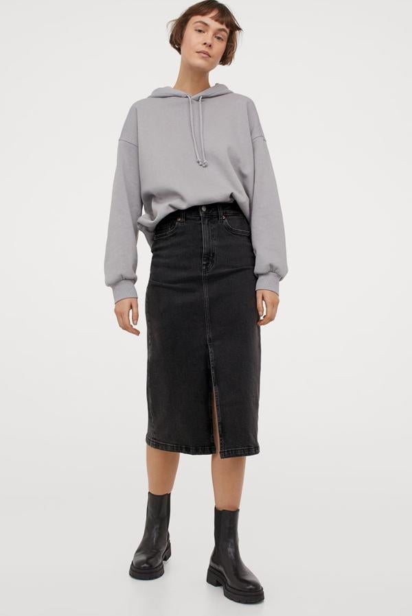 En denim elástico de algodón lavado, esta falda con cintura estándar, cierre de cremallera con botón y abertura delantera en el bajo es de H&M y tiene un precio de 29,99 euros. Podemos encontrarla entre las tallas 32 y 46.