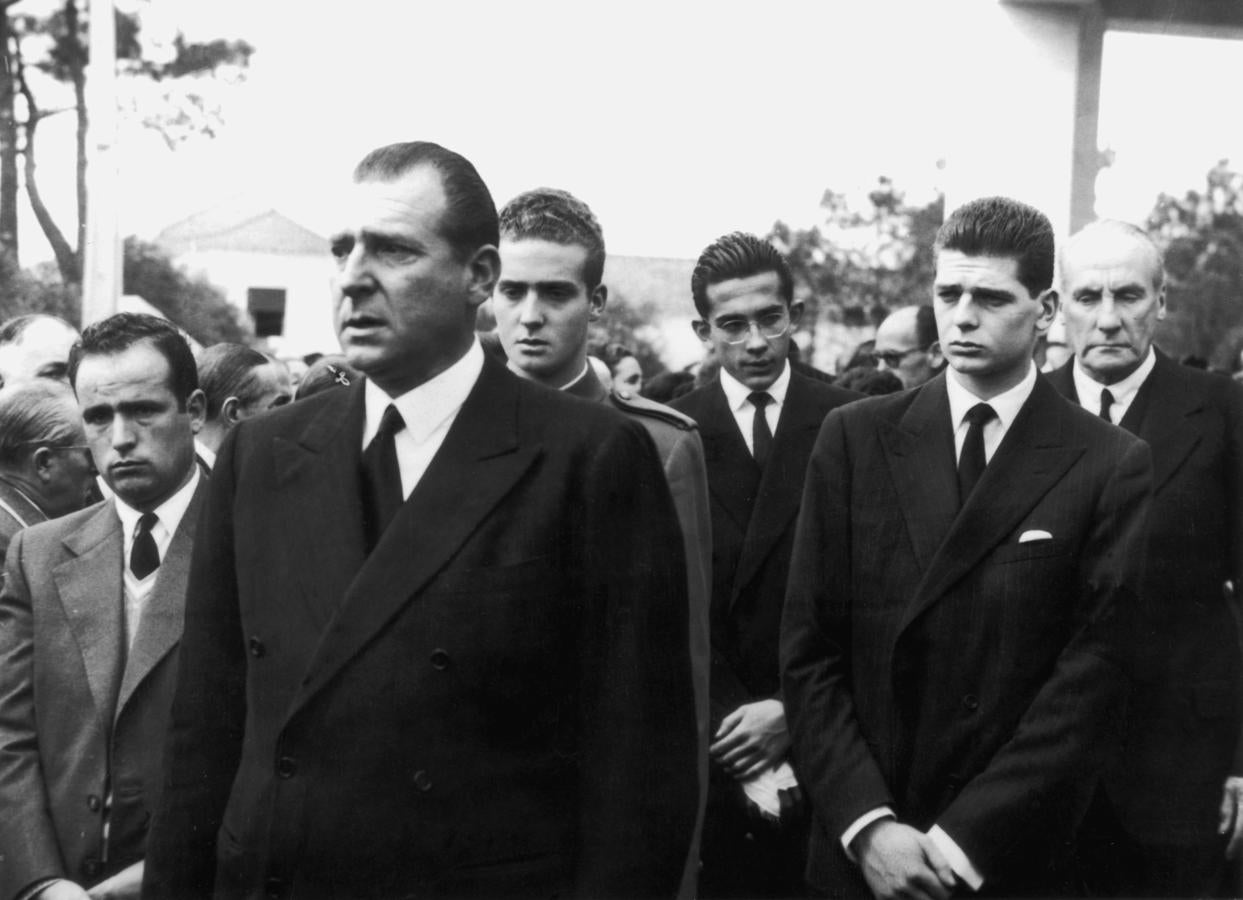 El 29 de marzo de 1956, Jueves Santo, don Juan Carlos mató a su hermano Alfonso. Pero todo fue un trágico accidente. Los dos hermanos jugaban con un revolver calibre 22 (regalo de Franco, para más detalles) y, sin saber que el arma estaba cargada, esta se disparó de forma accidental acabando con la vida del hijo de los Condes de Barcelona. Al principio la versión oficial aseguró que había sido el propio Alfonso el que tenía el arma en el momento del dramático incidente, pero pronto se supo que había sido don Juan Carlos quien la portaba en el fatídico instante. En la imagen, el Rey Emérito, tras su padre, durante el entierro de su hermano fallecido en Cascais.