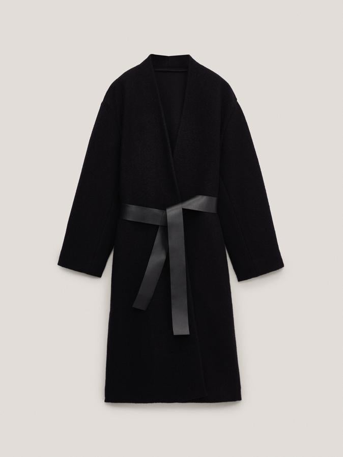 En color negro, con cierre de botón y cinturón de piel de estilo lazada, este abrigo de Massimo Dutti con dos bolsillos laterales tiene un precio de 199 euros y está disponible en las tallas S, M y L.