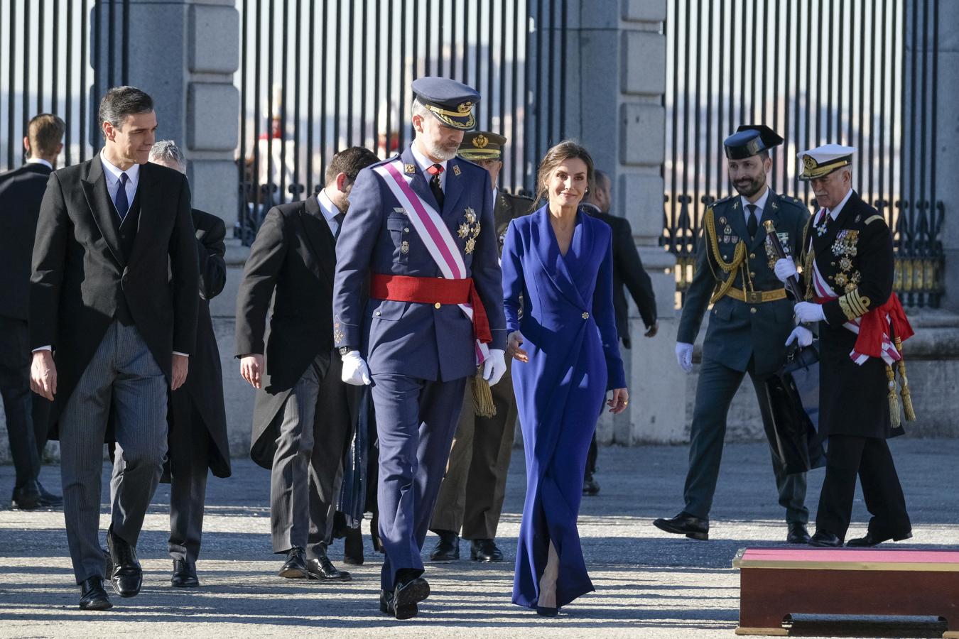 En 2020, la Reina Letizia lució su look más imponente y arriesgado en la Pascua Militar : un vestido 'classic blue' (color Pantone del año) de silueta 'wrap' rematada con botón joya, escote esmoquin y abertura en la falda. Su firma es aún desconocida.