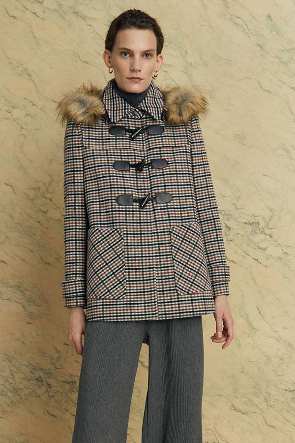 Con detalle de pelo en la capucha, este abrigo tipo trenka con estampado de cuadros cuenta con bolsillos delanteros y tiene un precio de 49,99 euros.