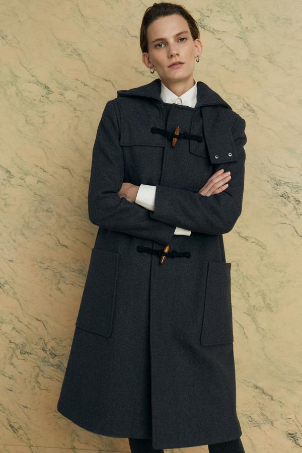 En color gris, este abrigo largo tipo trenka cuenta con cierre frontal de botones y capucha. Su precio rebajado es de 55,95 euros.