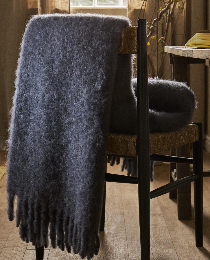 Disponible en color azul, mostaza o terracota, esta manta de lana cardada con acabado de flecos es lo más suave y cálida. Con unas medidas de 140x190 centímetros, tiene un precio de 99,99 euros.
