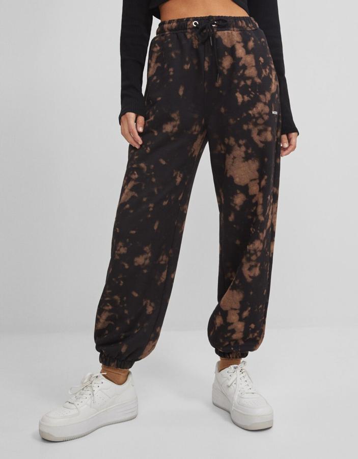 Bershka también apuesta por el estampado tie dye para los pantalones jogger, pero en este caso lo hace en negro con degradado en marrón claro. Con cintura elástica con cordón y bajos acabados en puño, de 19,99 euros ha pasado a 12,99 euros.