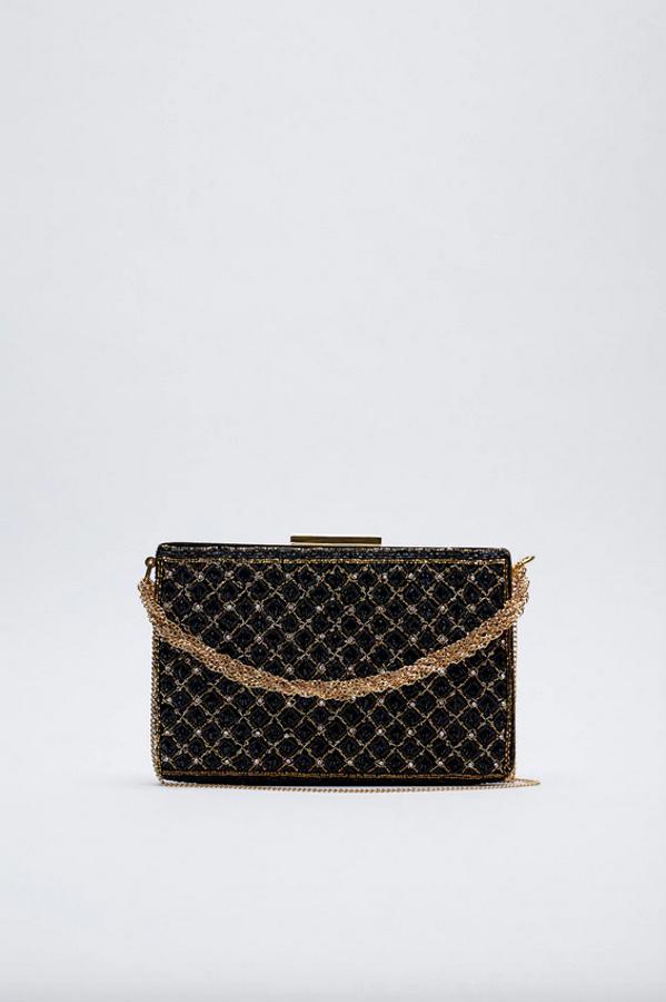 Esta bandolera plana en color negro es de Zara y viene con abalorios en el cuerpo con forma en la trama. Con asa de mano con cadena ancha y asa de hombro con cadena fina, el cierre superior es de pieza metalizada. De 49,95 euros ha pasado a costar 29,99 euros.