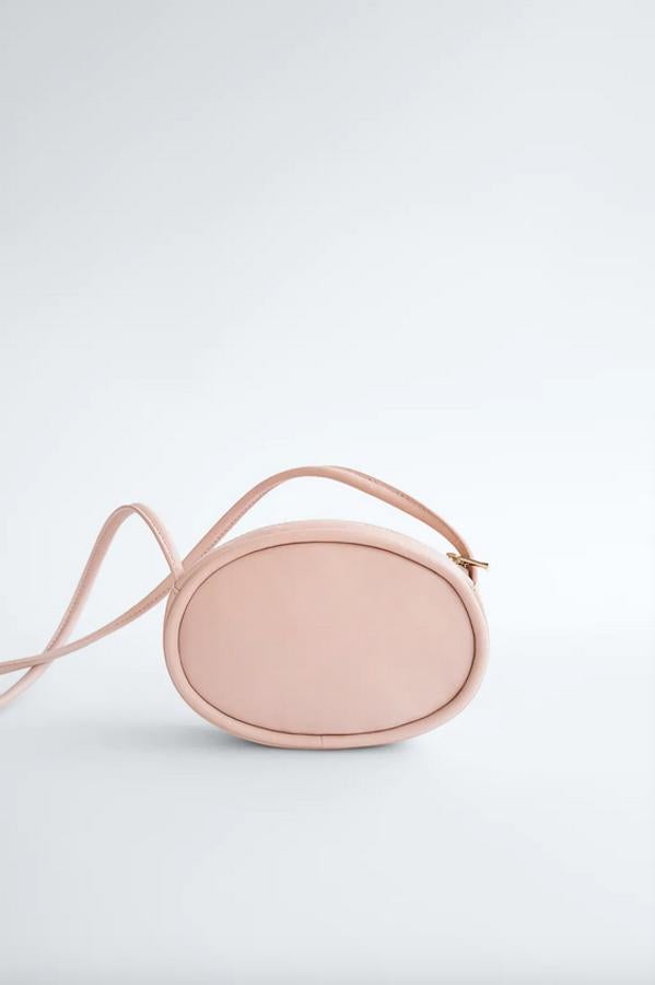 En formato mini ovalado, este bolso de piel de Zara con asa tubular de hombro y cierre de cremallera superior en dorado costaba 29,95 euros y ahora está por 15,99 euros.