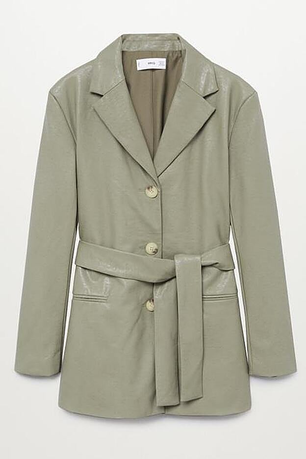 La americana, en tejido de efecto piel de color verde, cuenta con cinturón desmontable y diseño recto.