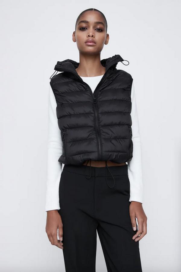 En tejido water repellent, con cuello subido ajustable con cordones elásticos y bolsillos con cremallera en el frontal, este chaleco negro de Zara que viene con bolsa para transportarlo tiene cierre frontal de cremallera. Podemos encontrarlo entre las tallas XS y XXL por 25,95 euros.