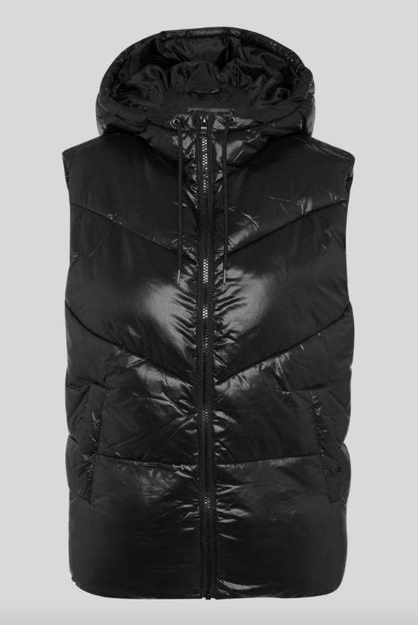 Con diseño en brillo mate, bolsillos laterales y cierre frontal de cremallera a tono, este chaleco acolchado negro de C&A con capucha tiene un precio de 24,99 euros y está disponible en las tallas 36 y 44.