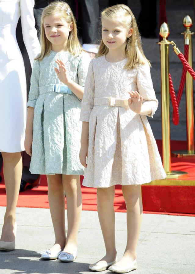 La infanta Sofía y la princesa Leonor en la ceremonia de coronación de su padre en 2014. Ambas optaron por el mismo vestido y bailarinas, aunque en diferente color. Hasta saludando parecían idénticas .