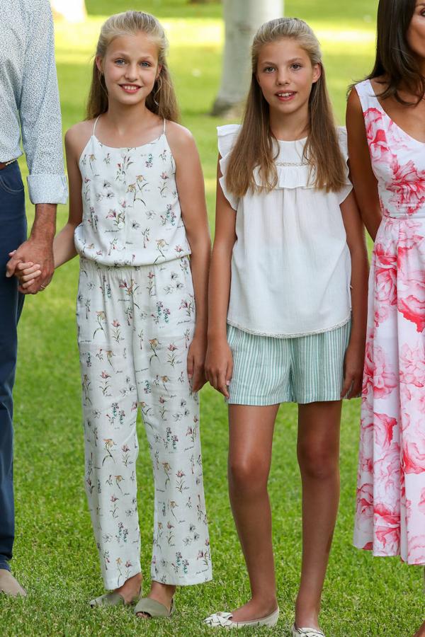 A medida que han ido pasando los años, la forma de vestir de las dos se va diferenciando. En esta ocasión, para el posado real en Mallorca, la princesa Leonor optó por lucir un mono con estampados florales. Su hermana la infanta Sofía eligió un pantalon corto con una camisa sin mangas de color blanco. Leonor completó el look con las clásicas menorquinas mientras que Sofía lo hizo con bailarinas.