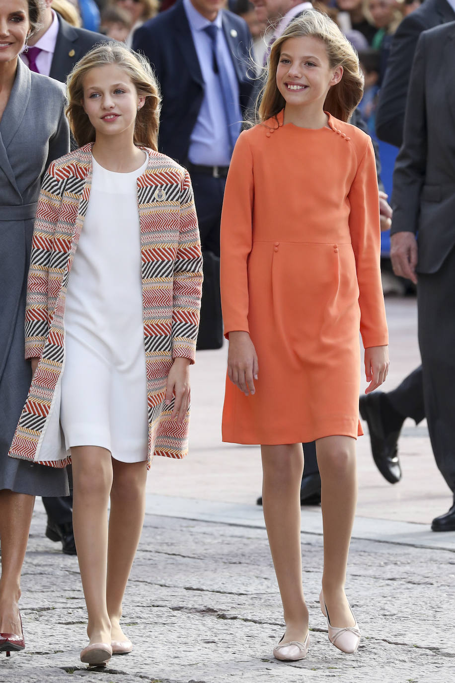 Para el primer día de llegada a los Premios Princesa de Asturias de 2019, la infanta Sofía deslumbró con un vestido naranja rematando el look con unas bailarinas con lazo y tacón. Por su parte, Leonor llevaba un vestido blanco fluido combinado con un colorido abrigo y unas bailarinas.
