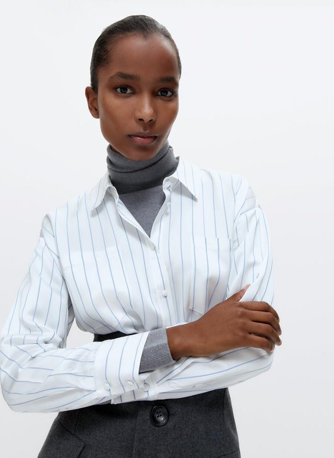 Confeccionada en un tejido satinado de alta calidad, esta camisa blanca con estampado de rayas finas en celeste viene con cuello clásico, dos bolsillos en la pechera y diseño oversize. Disponible en las tallas S y M, costaba 79 euros y ahora podemos comprarla por 49,95 euros.