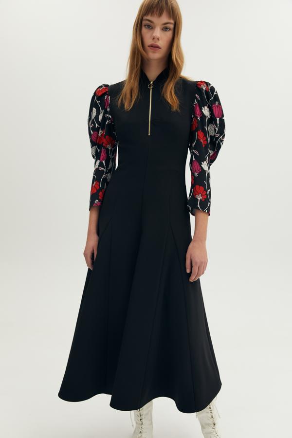 En color negro, con cuello mao y escote con cremallera, este vestido negro de Sfera viene con falda con vuelo, cuesta 39,99 euros y está disponible en las tallas S y M.