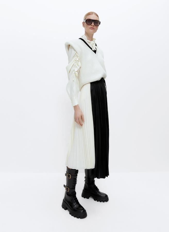 Confeccionada en dos tejidos contrastados en textura y color, blanco y negro, esta falda plisada de Uterqüe con cinturilla con hebilla metálica y detalle de bajo desestructurado con dos largos diferentes tiene un precio de 79 euros y está disponible entre las tallas XS y L.
