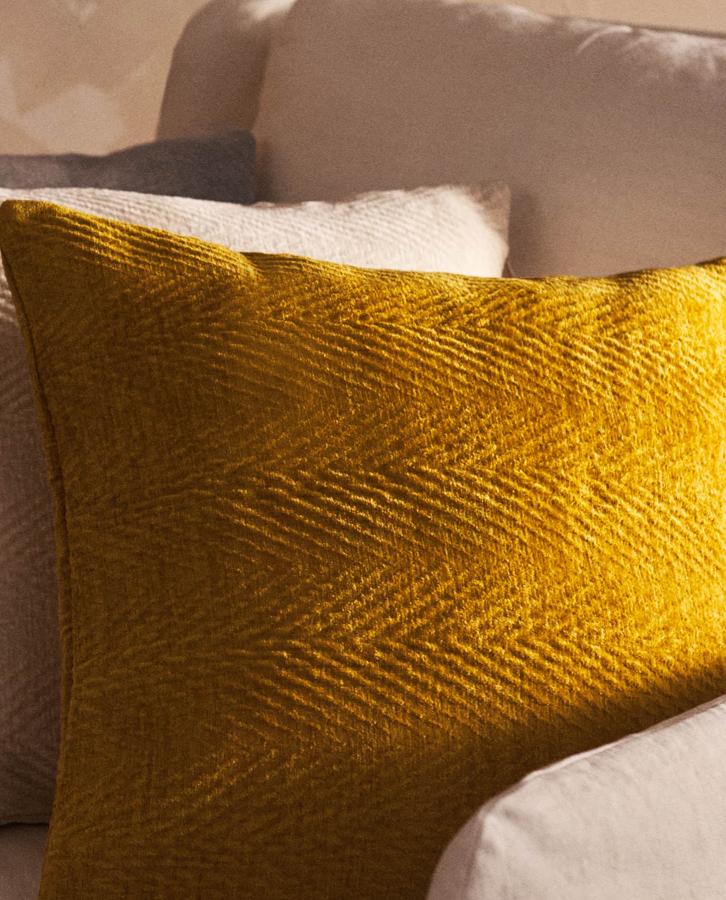 Disponible en mostaza o blanco roto, esta funda de cojín en chenilla tiene unas medidas de 45x15 centímetros y un precio de 19,99 euros.