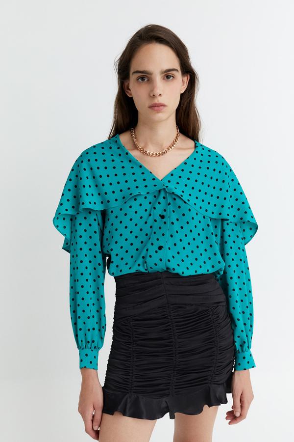 En color verde con lunares negros, esta camisa con volante y manga suelta terminada en puño con botón tiene ahora un precio de 15,99 euros.