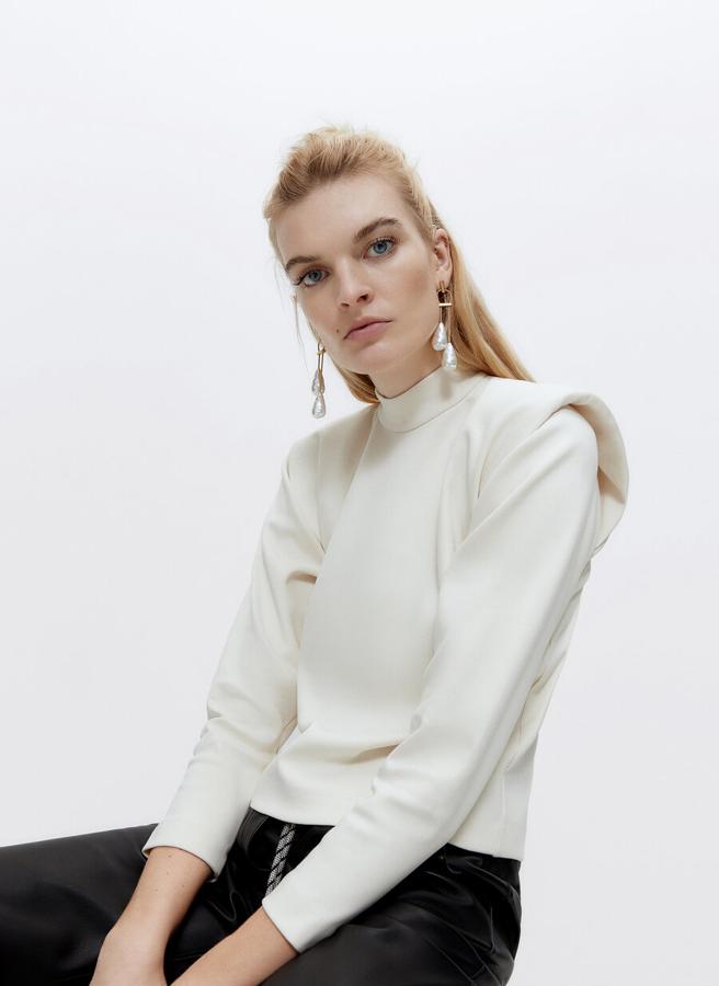 Con hombreras, cuello perkins y mangas largas, esta camiseta en color crudo con abrochado en la espalda de cremallera está disponible en las tallas S y M y cuesta 59 euros.