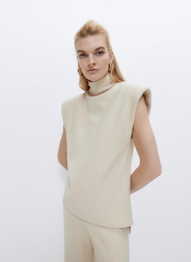 Punto perlado para este chaleco en color crudo con hombreras, cuello chimenea, acabados en rinb y aberturas laterales con bajo asimétrico. Cuesta 79 euros y estará disponible en las tallas S y M.