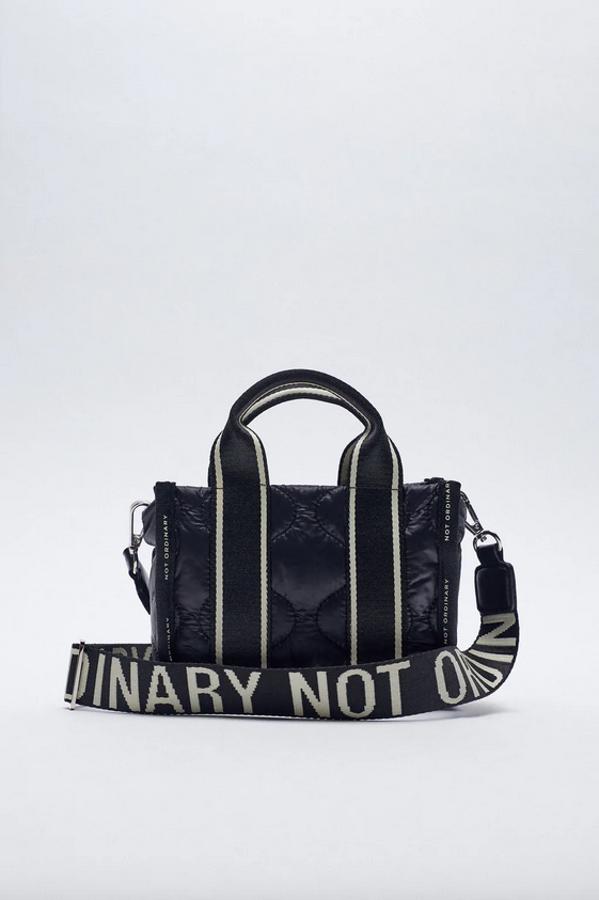 En formato mini y color negro, este bolso shopper de Zara con contrastes en crudo y mensaje en el contorno y el asa de hombro tiene el cuerpo de nylon acolchado con detalle de pespuntes y asas de mano. Con cierre superior de cremallera, cuesta 19,95 euros.