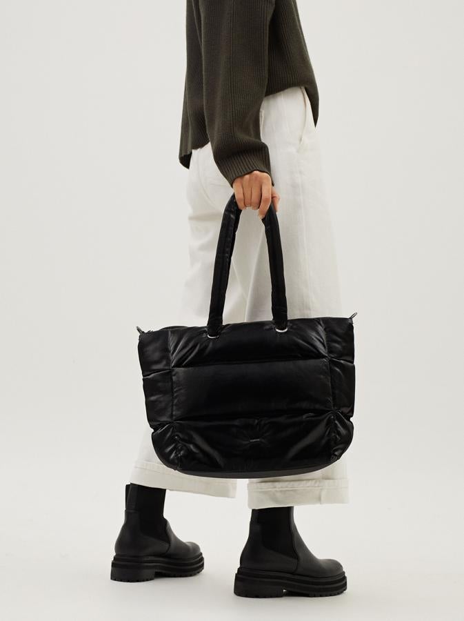 En color negro, con cuerpo y asas de mano acolchadas, este bolso de Parfois con cremallera superior y anillas metalizadas en las asas cuesta 29,99 euros.