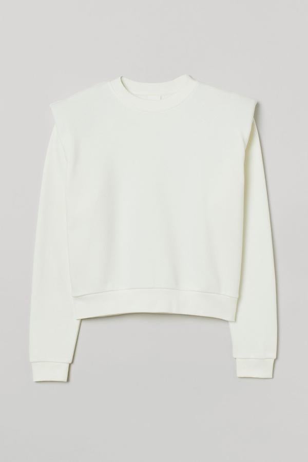 En color crema, con cuello redondo y hombros marcados con hombreras, esta sudadera suave en mezcla de algodón y poliéster reciclado viene con ribete elástico de canalé en el escote, puños y bajo. Tiene un precio de 14,99 euros y está disponible entre las tallas XS y XXL.