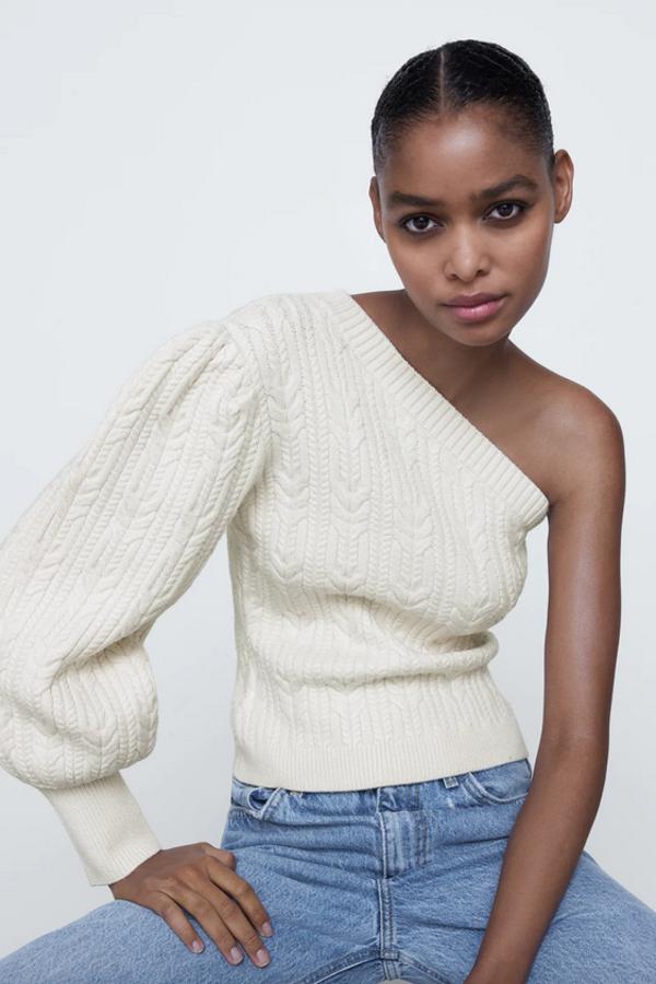 Diseño asimétrico de manga abullonada por debajo del codo para este jersey de punto blanco de Zara con detalle de ochos en el cuello y la manga y acabados en rib. Confeccionado con al menos un 50% de viscosa sostenible, tiene un precio de 25,95 euros y está disponible en las tallas S, M y L.
