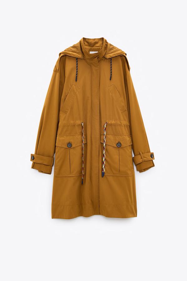 Trench de cuello subido con capucha y cintura ajustable con cordón y manga larga, de Zara (29,95 €).