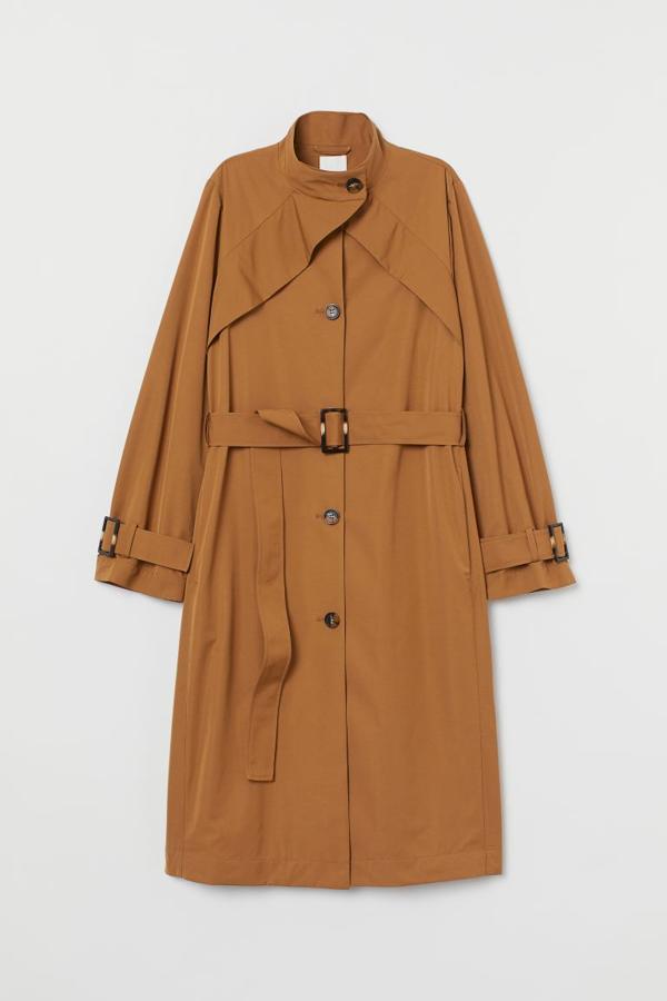 Gabardina ligera en tejido fresco con cuello elevado, botones delante y canesú en la espalda, con cinturón extraíble, bolsillos en las costuras laterales, tira ajustable de quita y pon en los puños y abertura detrás, de H&M (59,99 €).