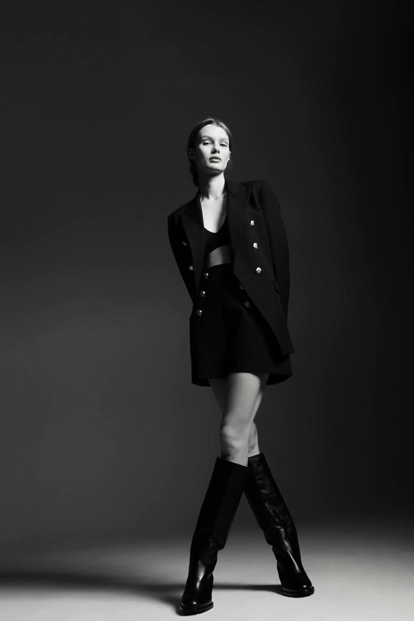 Este traje negro con botones dorados tiene todos los ingredientes para ser nuestro favorito de la nueva colección de Zara: es elegante, versátil y muy favorecedor. Nos encanta en 'total look' y para llevar por separado. ¿Su precio? 79.95 euros la blazer cruzasa y 29.95 euros los shorts de cintura alta y marcada que hacen más delgada.