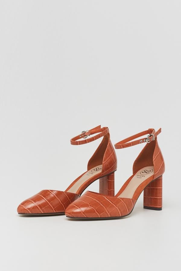 Este zapato de tacón con efecto cocodrilo en color naranja y cierre mediante pulsera al tobillo tiene un precio de 25,99 euros.