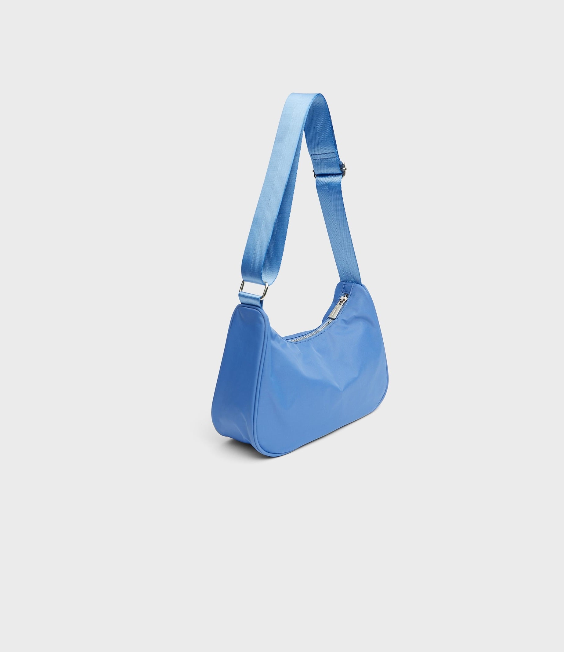 Bolso baguette con tejido de nylon y asa ancha de Stradivarius. Disponible también en rosa pastel y en negro por 12,99 euros. Un básico que combina con absolutamente todo.