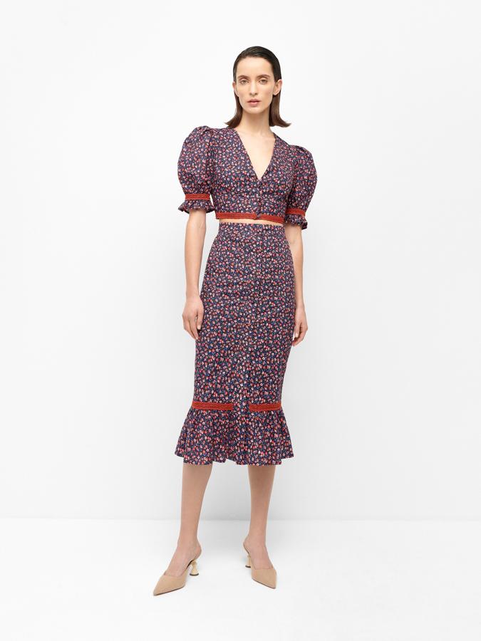 Una falda midi con estampado de flores acompañada de una blusa cropped de manga francesa y escote en pico.