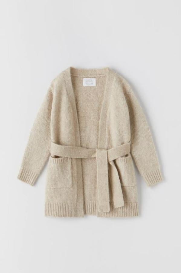 Unbásico que, esta vez, podrás llevar a juego con tu hija: esta chaqueta larga de punto beige con cinturón cuesta 19.95 euros en Zara Kids.