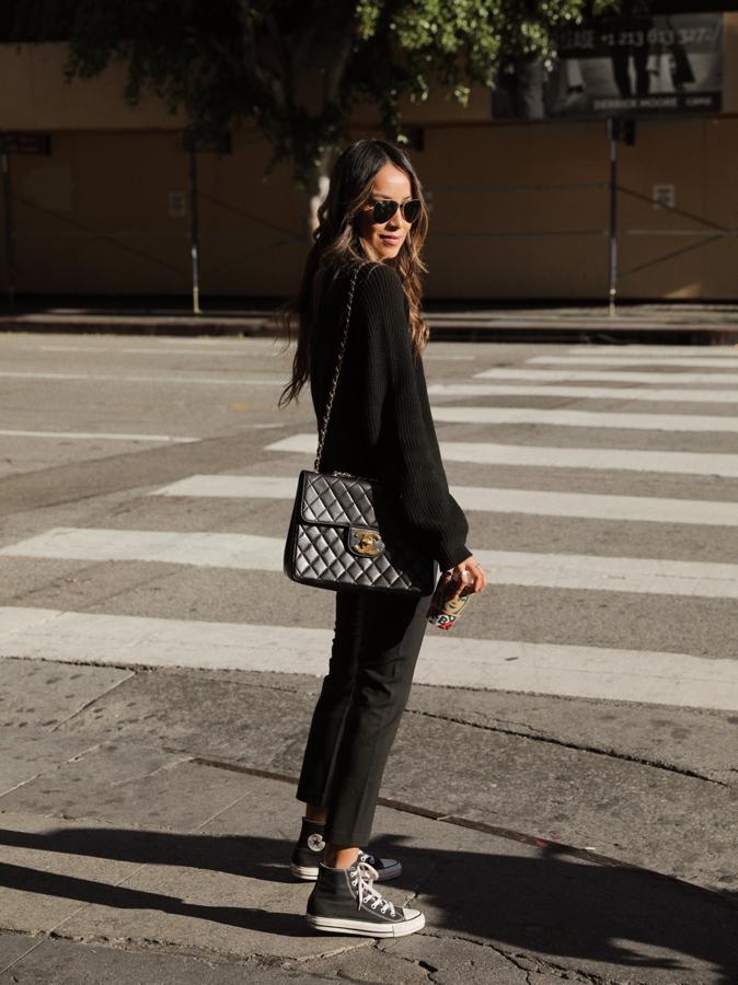 Jersey de punto negro + vaqueros rectos + bolso acolchado con cadena dorada 2.55 de Chanel + zapatillas Converse en color negro