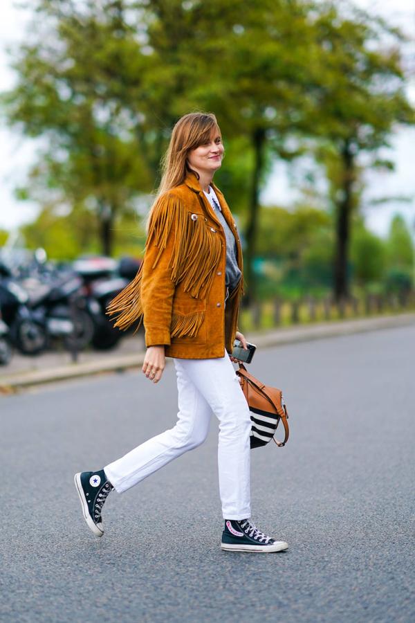 Cazadora de ante marrón con vaqueros blancos y zapatillas.