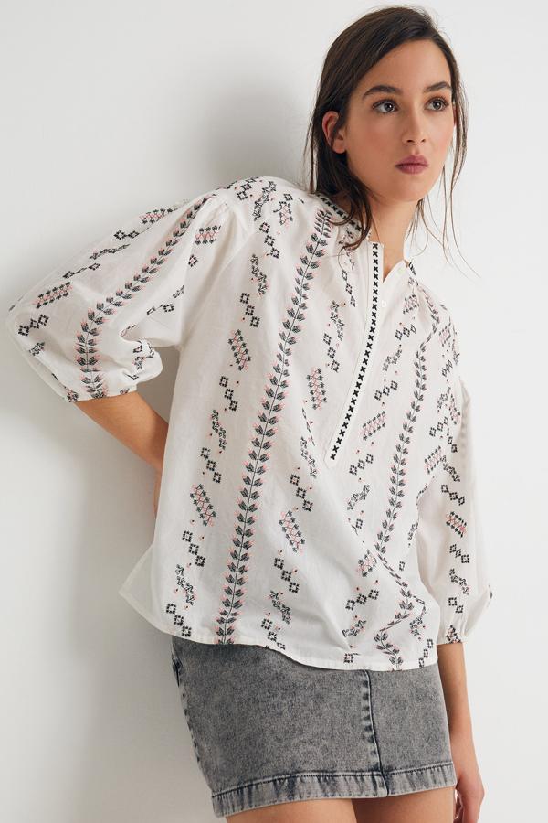 Confeccionada en 100% algodón de color blanco, esta blusa ancha con bordados y botones en la parte delantera tiene un precio de 23,99 euros.
