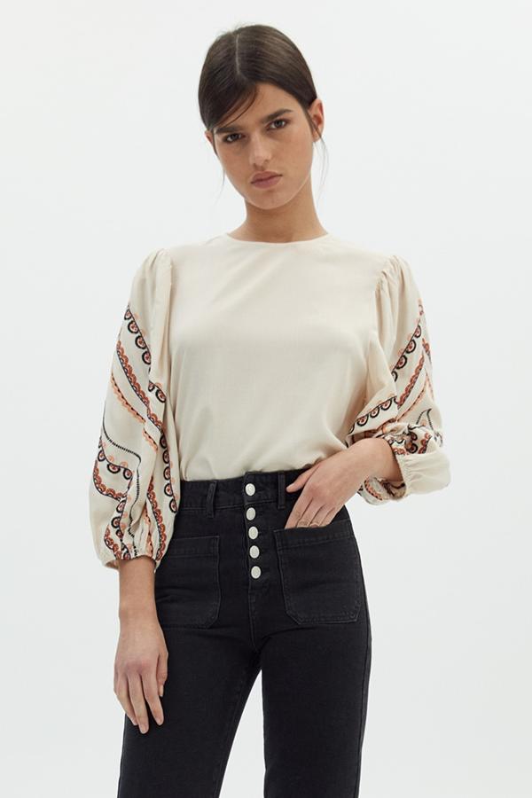 En color crema, este top liso con manga fluida con bordados cuenta con cierre trasero de lágrima y tiene un precio de 17,99 euros.