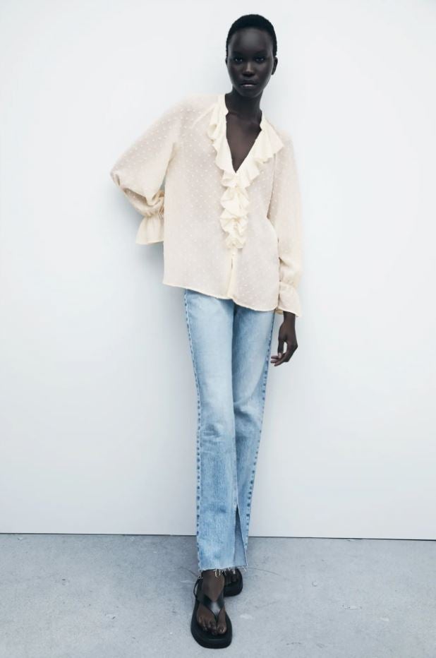 Esta blusa de plumetti semitransparencias y volantes en el escote cuesta 25.95 euros en Zara.