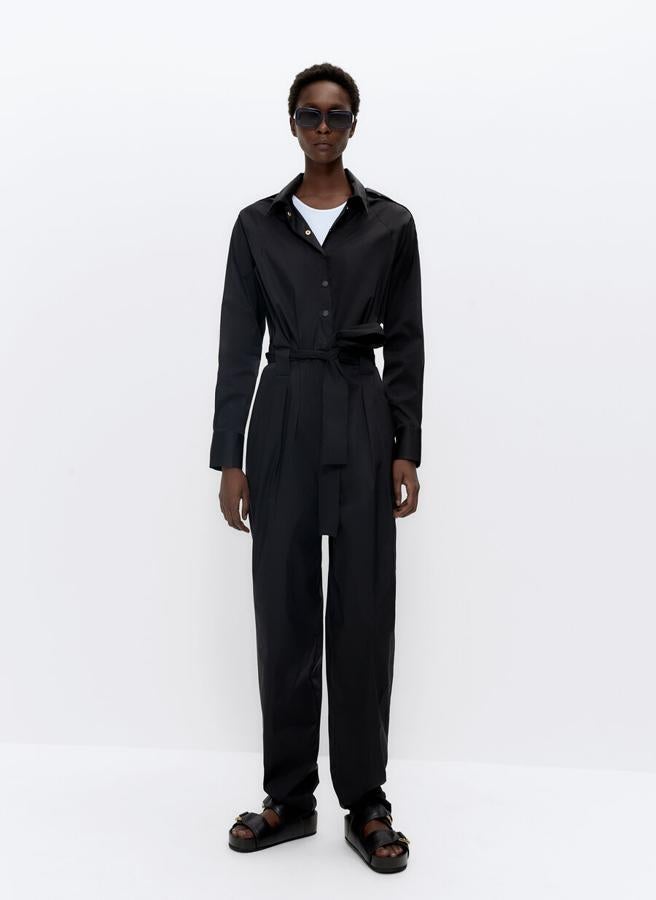 En Uterqüe hemos encontrado este mono negro confeccionado en tejido con efecto técnico, con manga ranglán con detalle de charreteras en los hombros, cuello camisero y cinturón a tono en el pantalón con pliegues. Disponible en las tallas S, M y L, cuesta 99 euros.