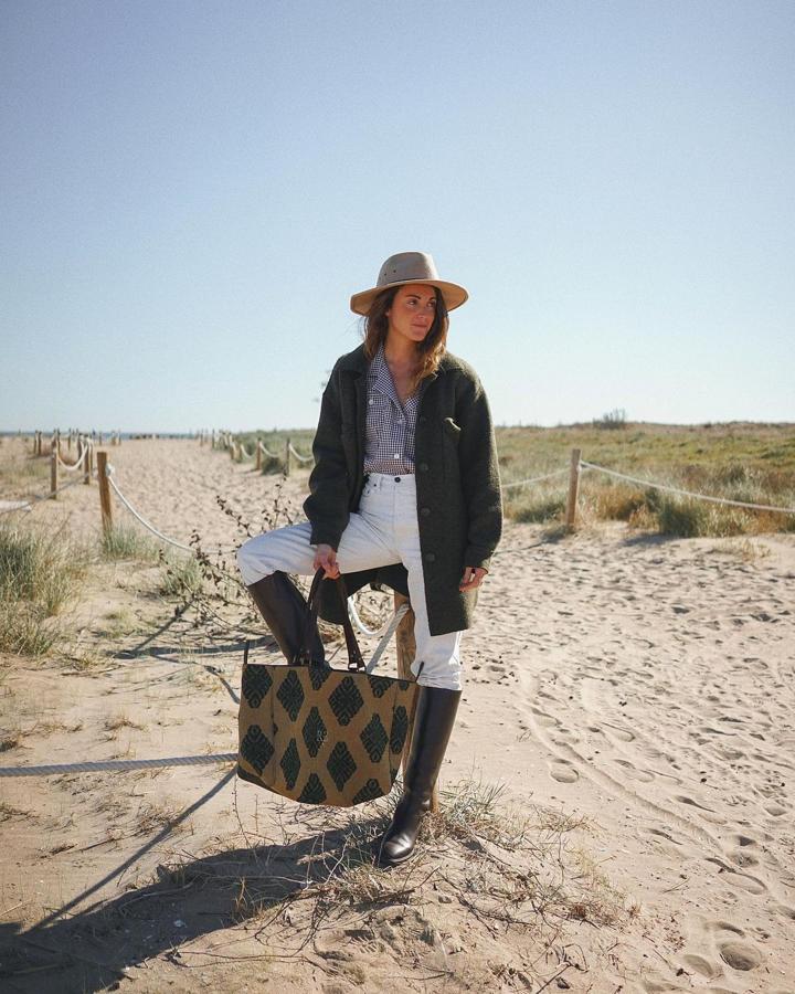Chaqueta caqui + pantalón blanco + botas altas + bolso estampado (@mirenalos)