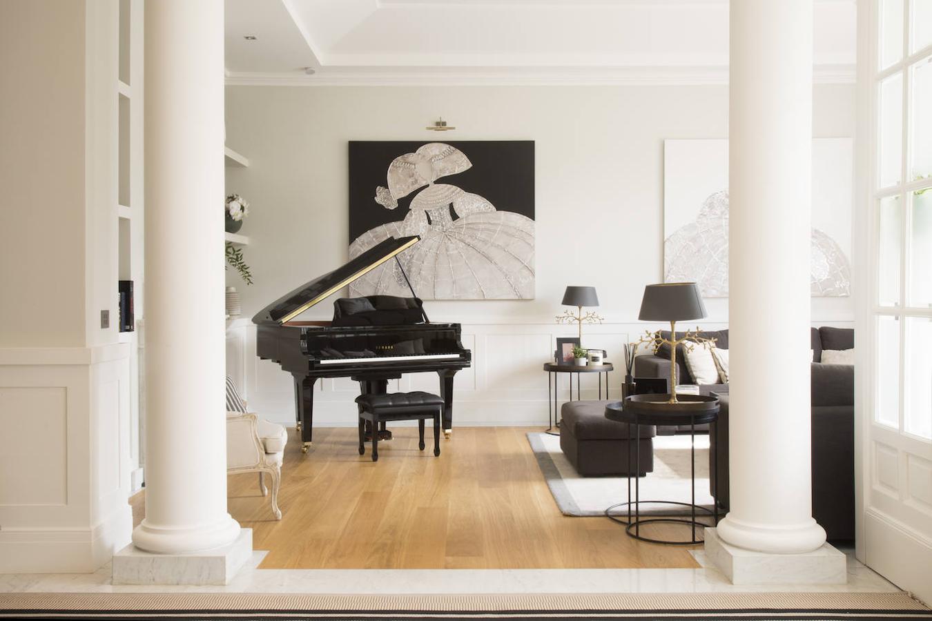 En una de las zonas del salón se ha colocado un piano. El cuadro está hecho a medida por Merck&Cia; las lámparas son de Villa Alys y los sofás, de Home Spirit. La alfombra es el modelo Sweet de Papiol y las mesitas auxiliares, de Notre Monde.