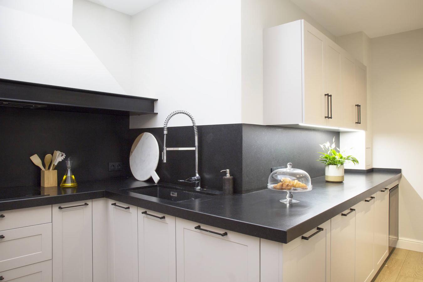 Zona de trabajo de la cocina, con puertas lacadas de Leicht. La encimera es de granito negro. El revestimiento del suelo es porcelánico imitando madera, de Porcelanosa.