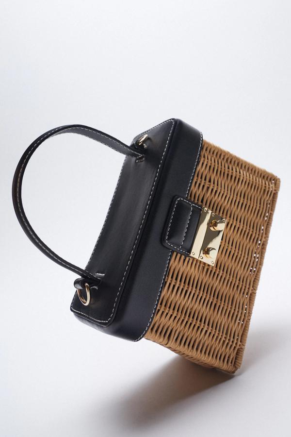 Este bolso con formato caja cuenta con el cuerpo de ratán en color natural y detalles en negro. Con asa de mano y asa de hombro extraíble con cadena, es de Zara y tiene un precio de 29,95 euros.
