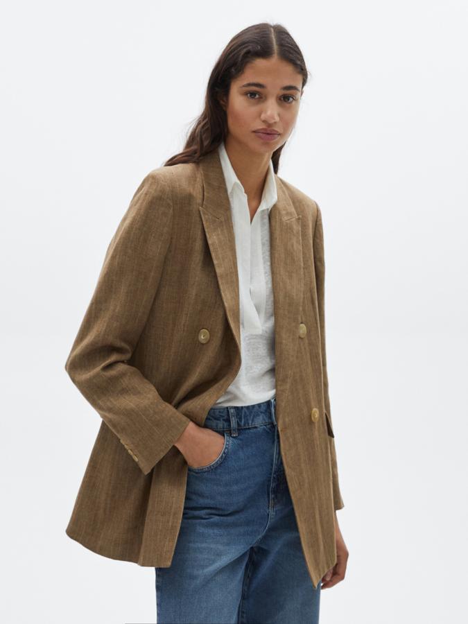 Con diseño de rayas en crudo, esta americana en marrón claro, con cuello de solapa de pico, cierre cruzado de doble botonadura frontal y dos bolsillos de solapa viene con puños abotonados y posibilidad de pantalón a juego. Cuesta 129 euros y podemos encontrarla entre las tallas 34 y 44.