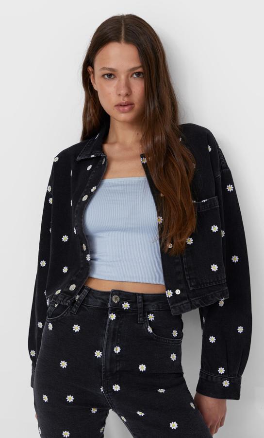 En tejido vaquero de color negro y con bordado de margaritas, esta cazadora con puños abotonados y bolsillos delanteros tiene un precio de 35,99 euros.