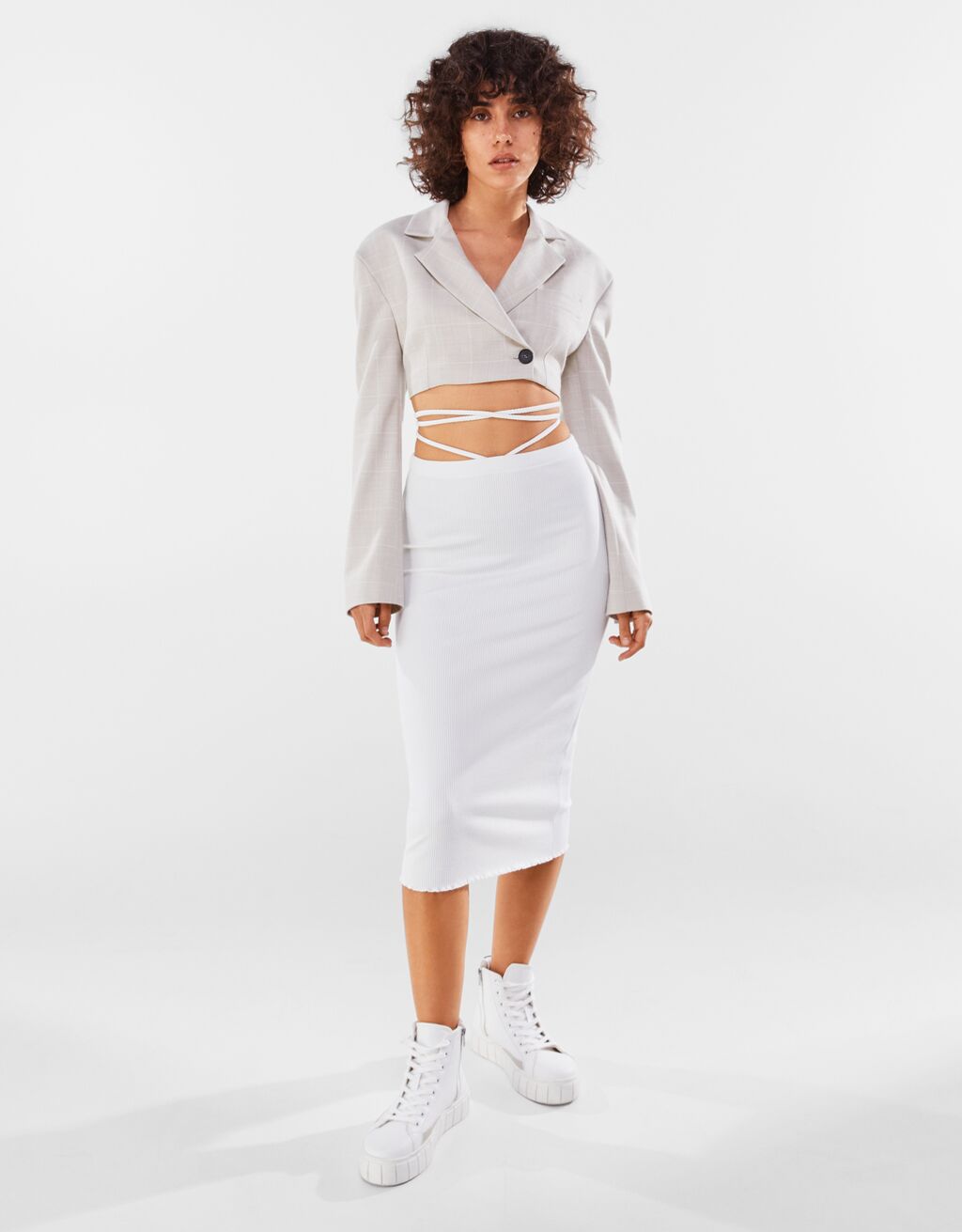 Falda blanca de punto entallado con tiras cruzadas en la cintura para un toque original y sexy. De Bershka por 19,99 euros.