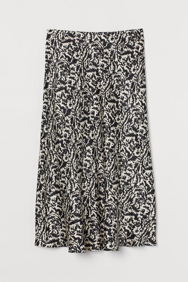 En tejido de viscosa, con estampado en tonos negros y beige claro, esta falda midi de H&M de talle alto con elástico oculto tiene un precio de 24,99 euros y está disponible entre las tallas XS y XXL.