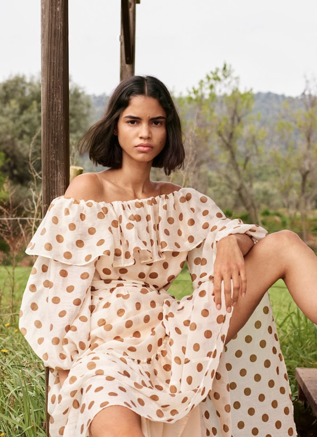 Impresionante vestido de lunares y volantes, con escote asimétrico, manga abullonada y cinturón ajustable. Está confeccionado en un tejido con lyocell y lo tienes en la nueva colección de Mango por 59,99 euros.